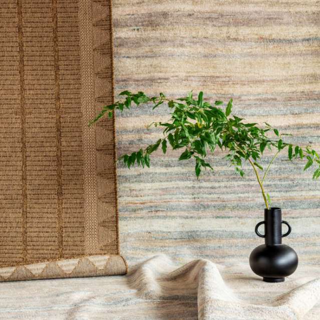 Black vace with green branches sitting on rugs